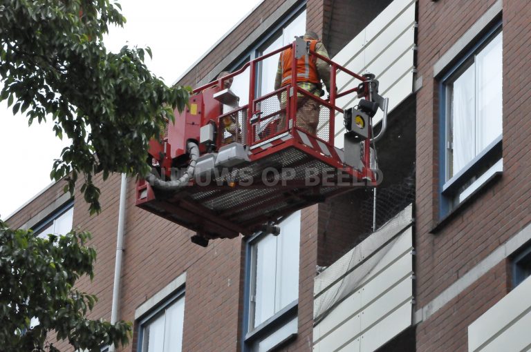 Brandweer haalt duif uit duivennet op balkon Weegschaalhof Rottedam