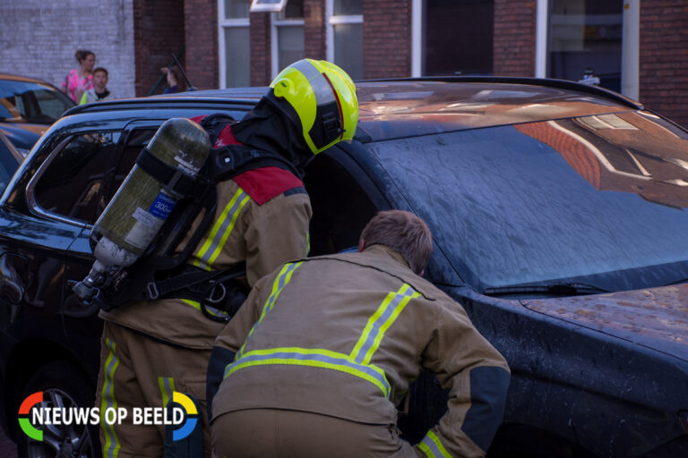 Omstanders blussen brandende auto in Den Haag