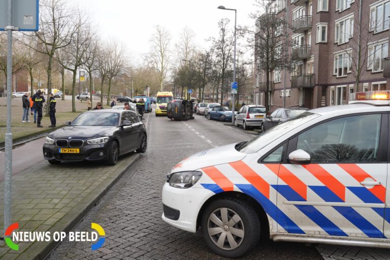 Auto op zijn kant na ongeluk Noordplein Rotterdam