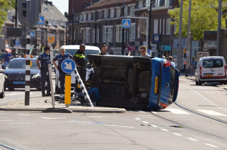 Auto crasht en belandt op zijn kant op kruising Rozenlaan-Kleiweg in Rotterdam