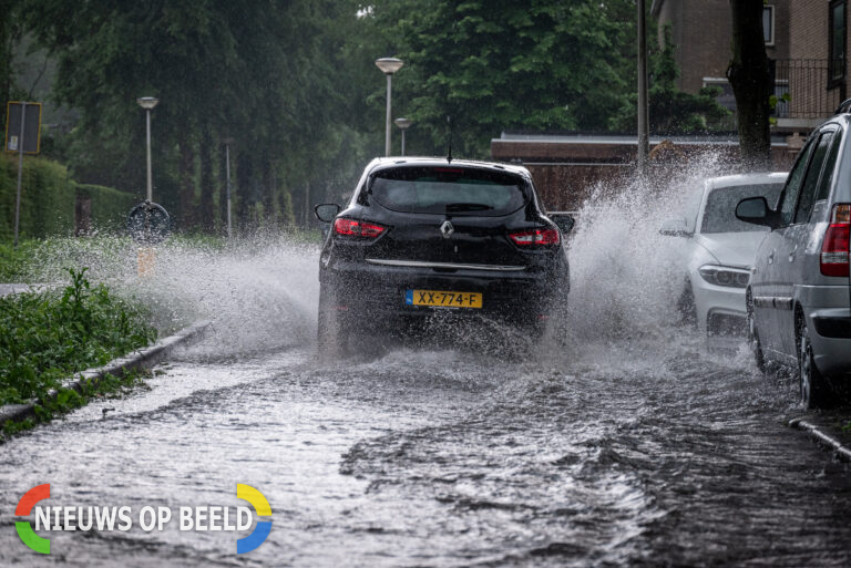 Straten en restaurant onder water na stortbui Stationsweg Heenvliet